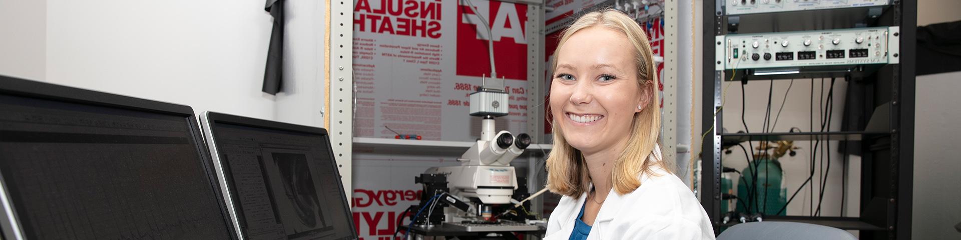 GNTP Student at a microscope smiling